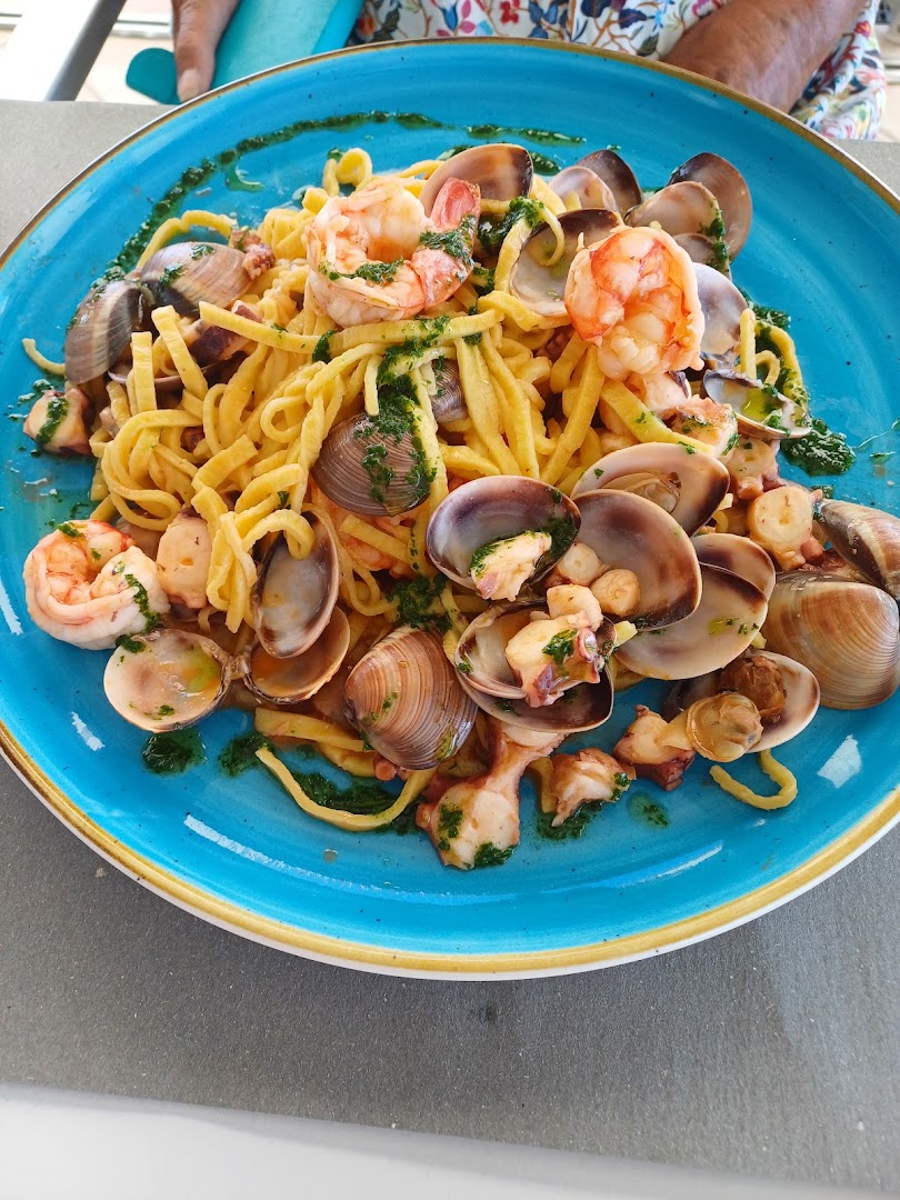 Piatto di tagliolini allo scoglio con vongole, gamberi e calamaretti su ceramica turchese